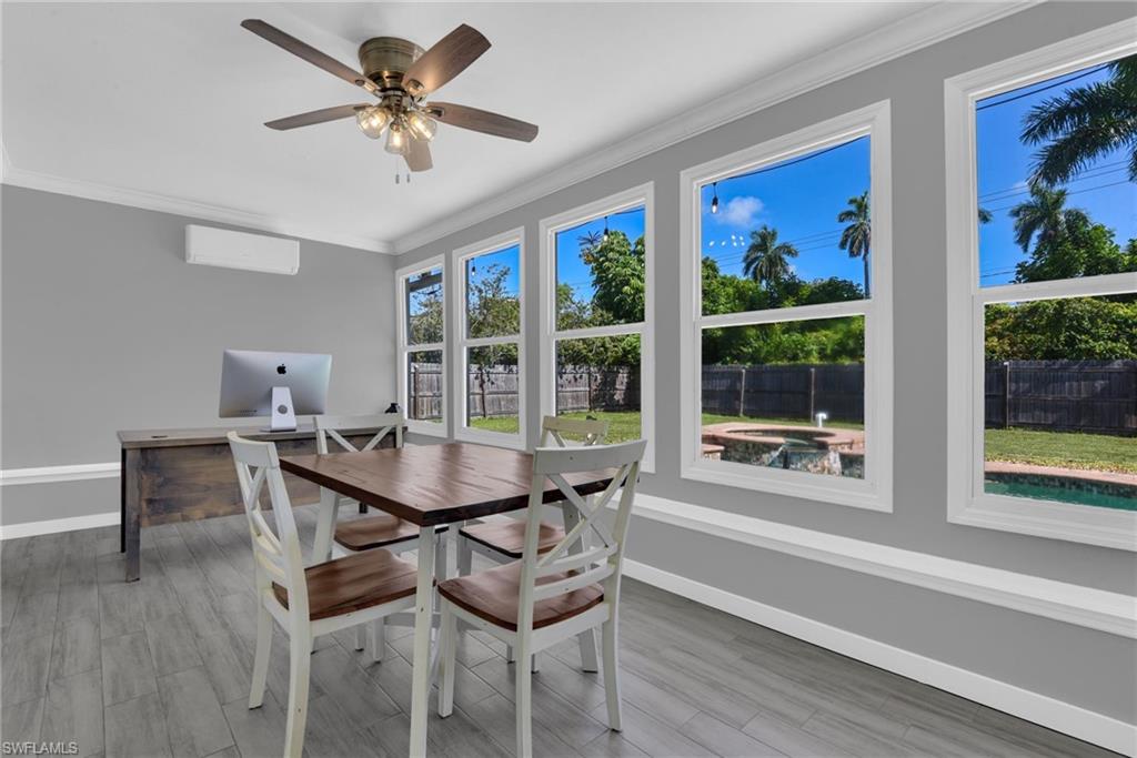 Wood-finish flooring, multiple windows, crown molding, ceiling fan, and wall-mounted air conditioning unit