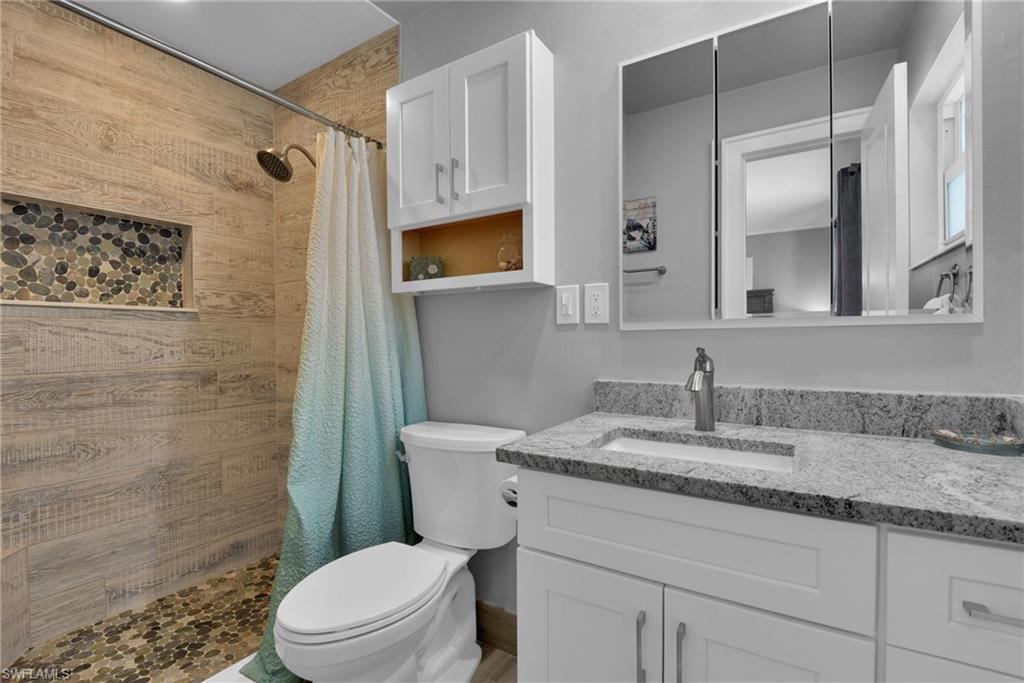 Shower featuring wood-look tile surround and pebble tile flooring with a built-in niche