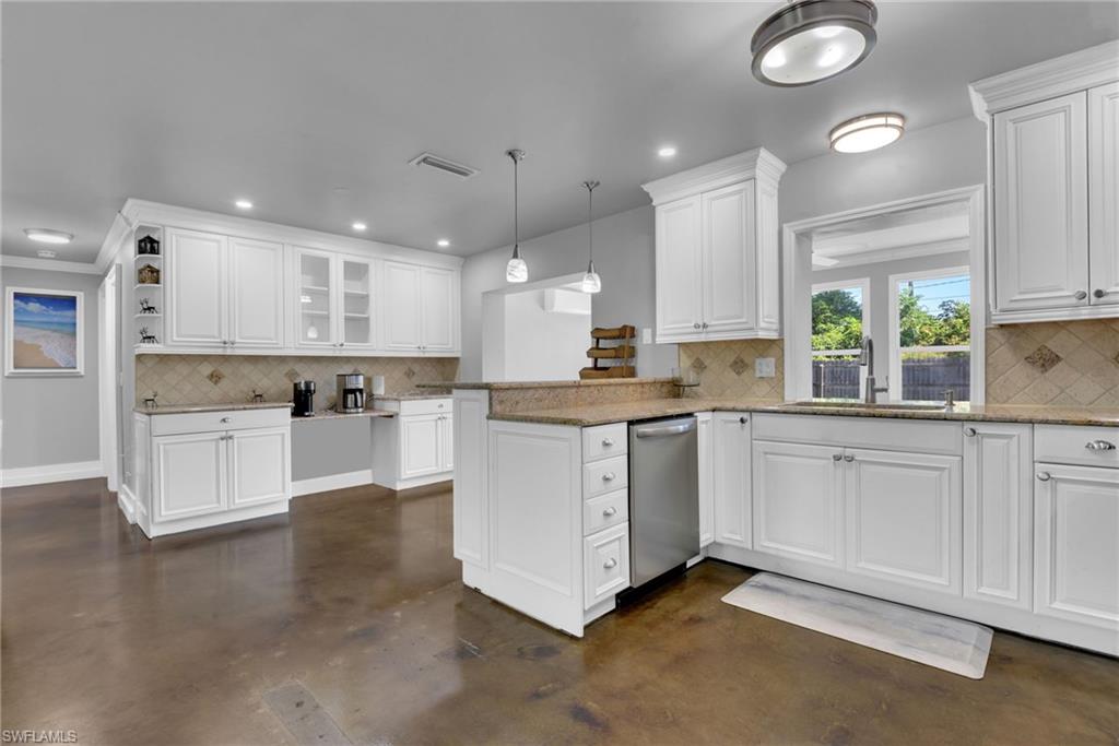 Kitchen featuring white cabinetry, granite countertops, stainless steel dishwasher, tile backsplash, and polished concrete flooring