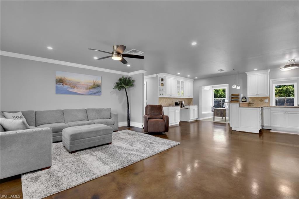 Expansive open-concept living space with polished concrete flooring, recessed lighting, and a ceiling fan