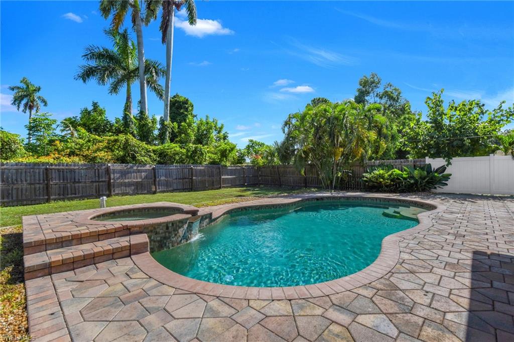 Private backyard with an integrated pool and spa, surrounded by paver decking and mature landscaping