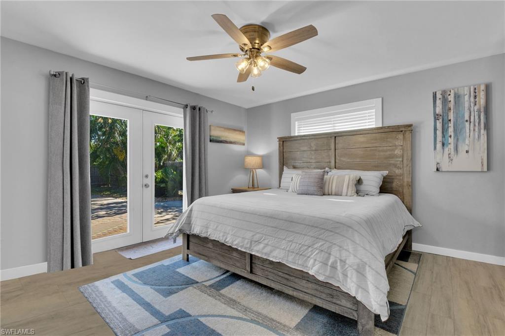 Wood-finish flooring, ceiling fan with integrated lighting, white frame French doors, and recessed window with blinds