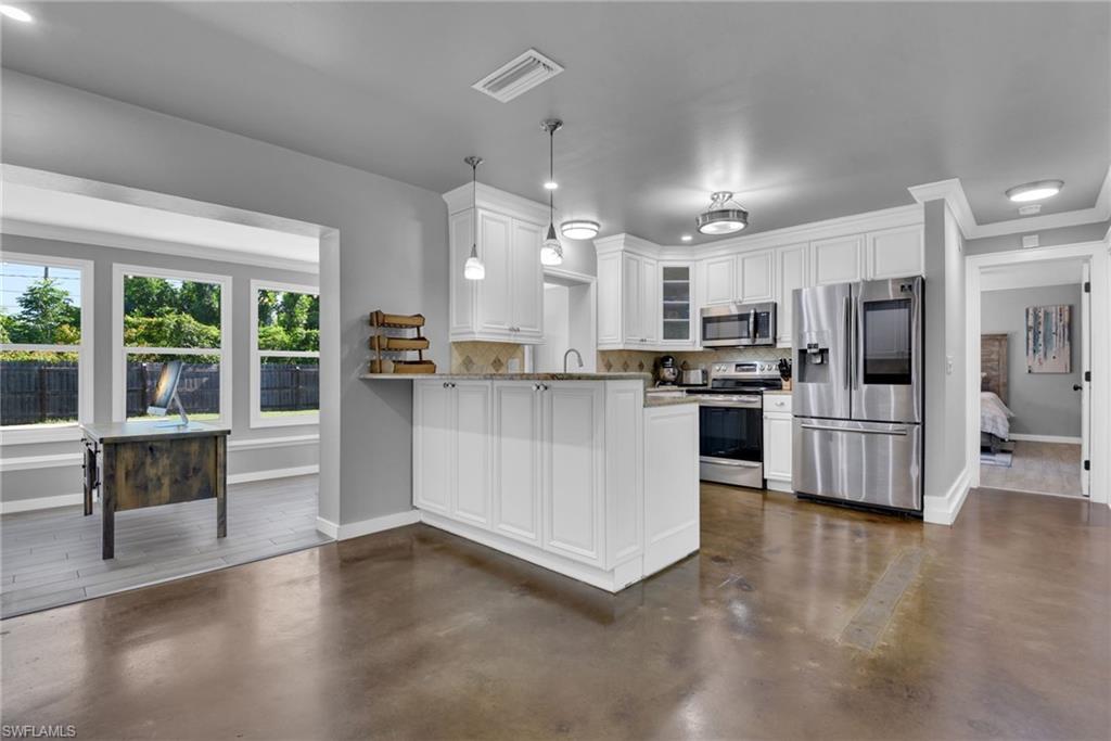 Kitchen featuring white shaker cabinetry, stainless steel appliances, pendant lighting, and a neutral tile backsplash