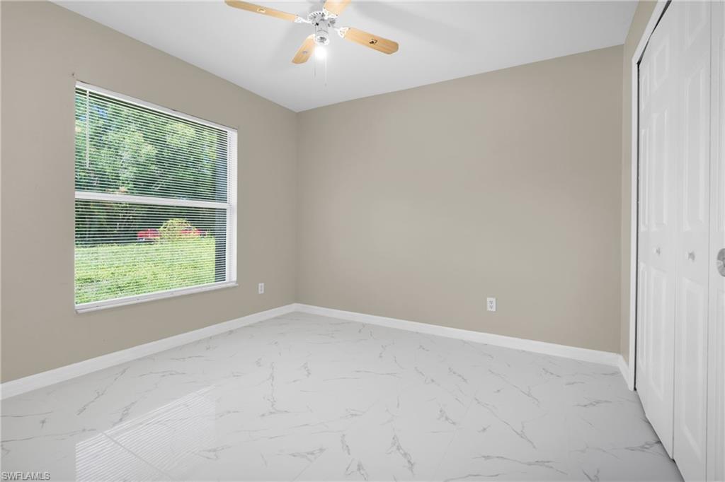 White tile flooring with grey veining, neutral wall paint, and a window with horizontal blinds