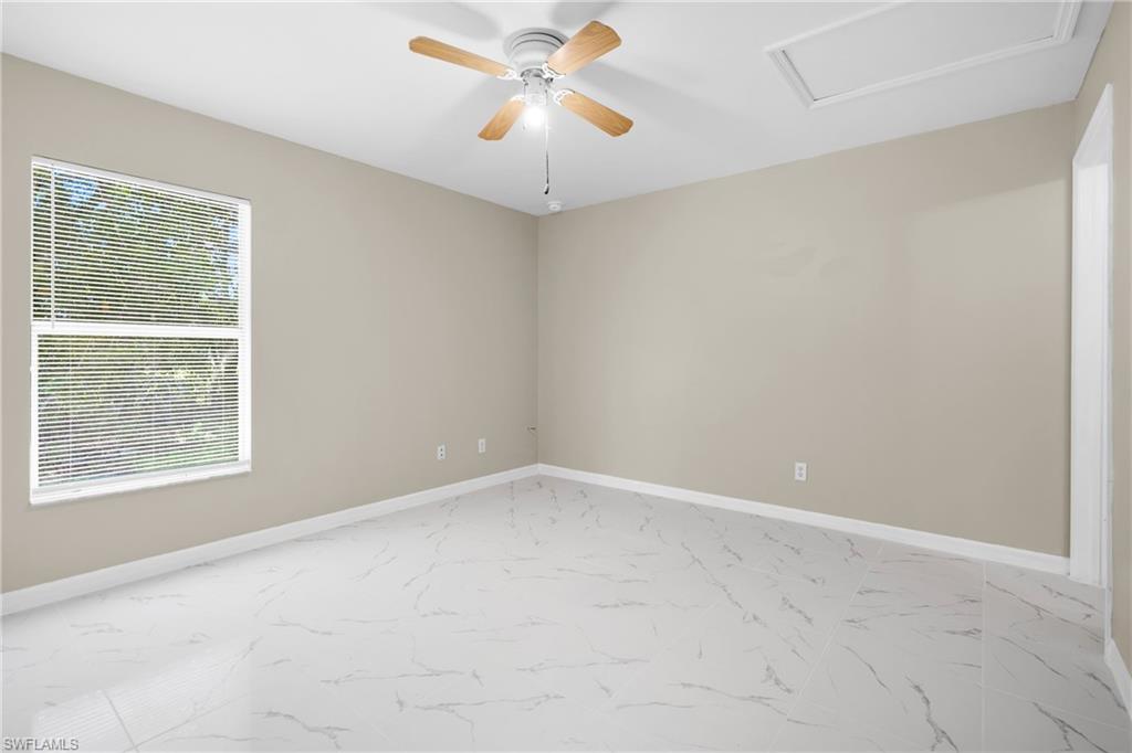 White tile flooring, a ceiling fan with light fixture, neutral wall paint, and a large window