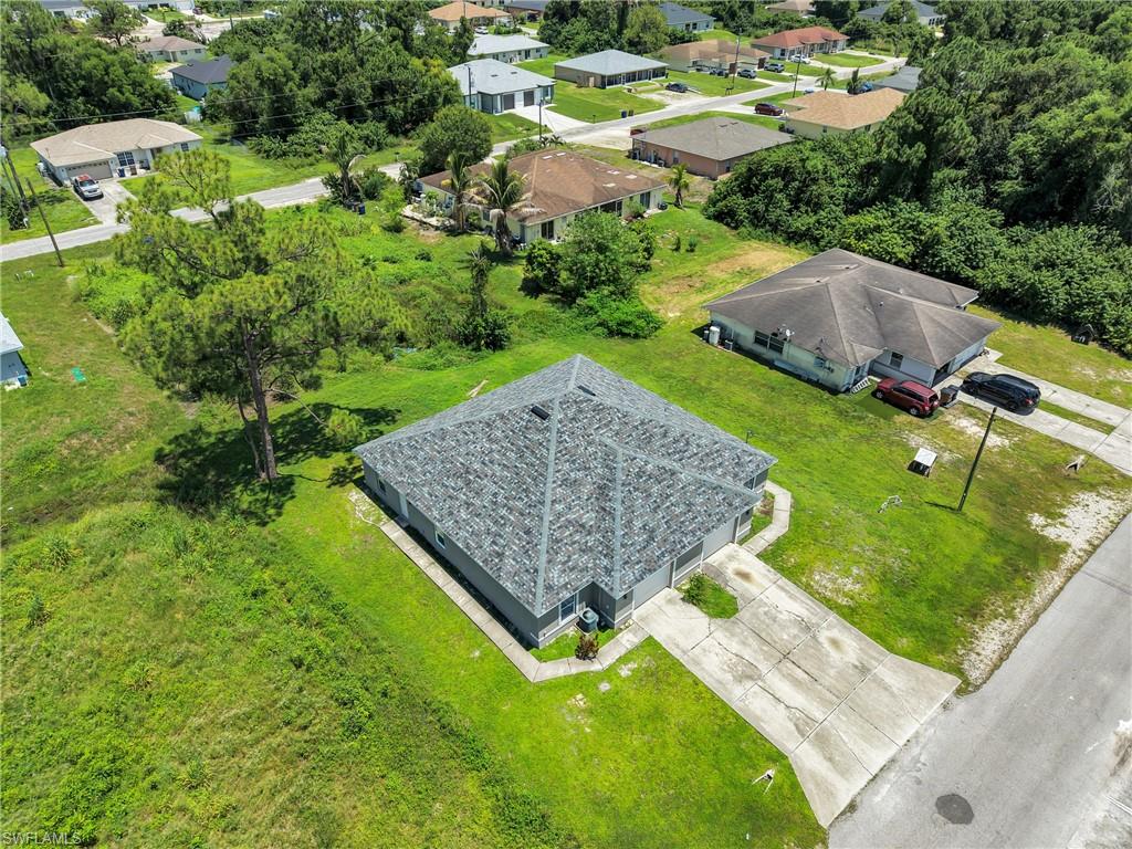 Recently constructed residence featuring a gray shingle roof, light-colored exterior, and an expansive lawn