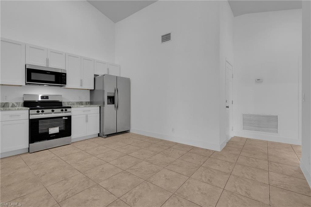 Kitchen featuring stainless steel appliances, white cabinetry, and light-toned tile flooring