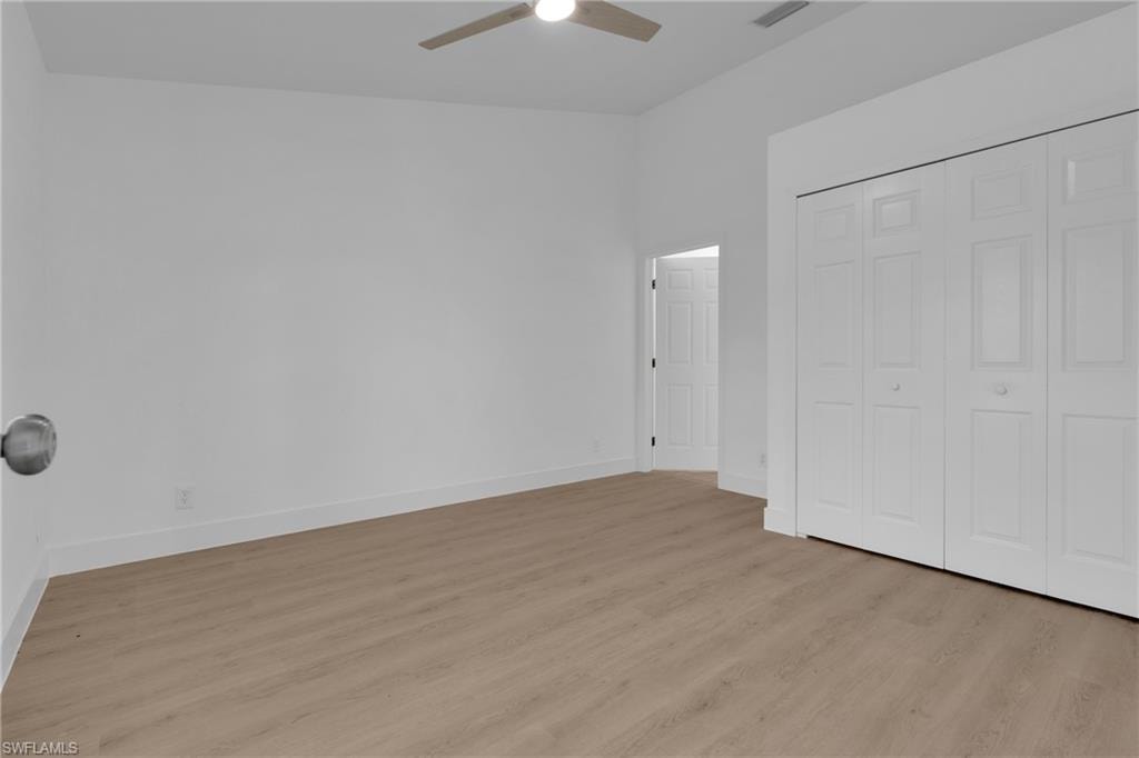 Wood-finish flooring, white walls, white bi-fold closet doors, and an overhead ceiling fan