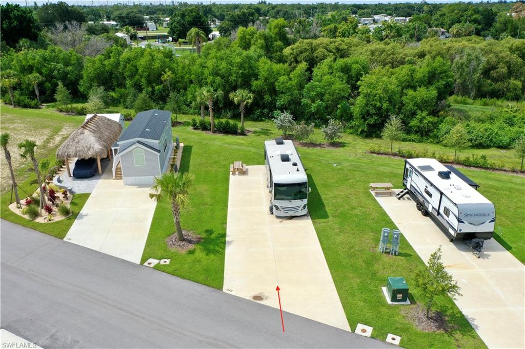 Expansive green spaces featuring paved driveways, a thatched-roof carport, and mature trees