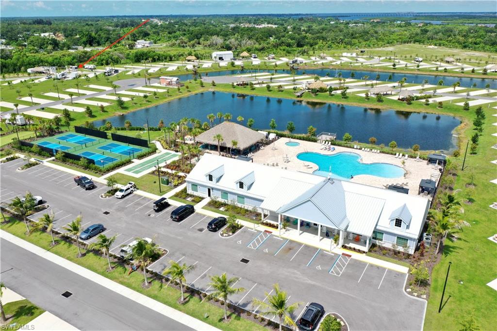 Clubhouse with an outdoor swimming pool, multiple sports courts, and a paved parking lot