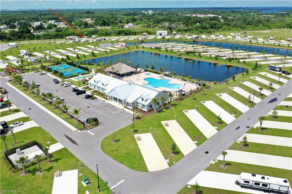 Community clubhouse with an expansive swimming pool, adjacent tennis courts, and established palm trees