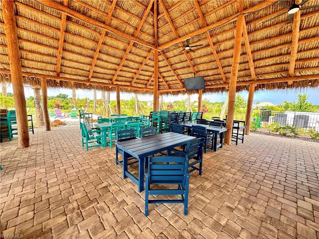 Thatch roof pavilion featuring wood beams, ceiling fans, and a mounted television