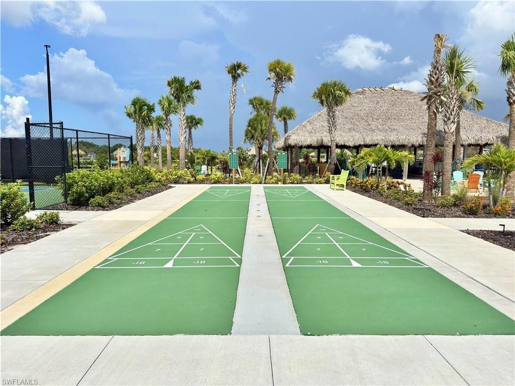 Dual shuffleboard courts, tennis court, and a thatched-roof building