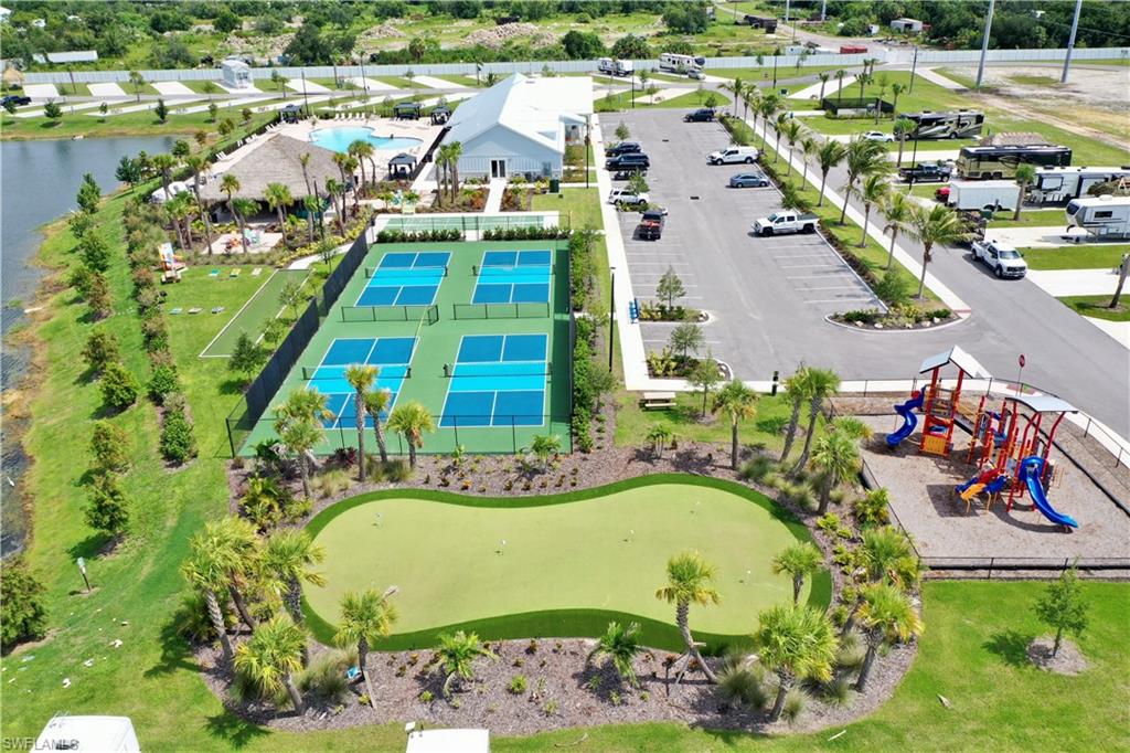 Recreational area featuring multiple pickleball courts, a putting green, a playground, and a swimming pool with a tiki hut