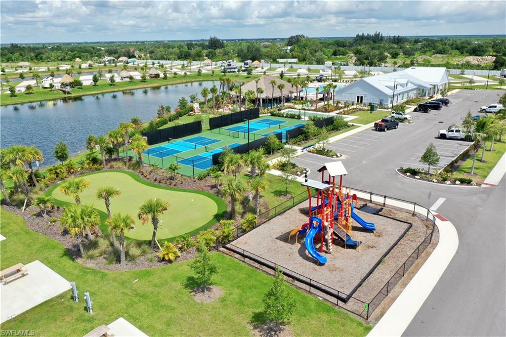 Lakeside setting featuring a putting green, multiple pickleball courts, and a dedicated playground area