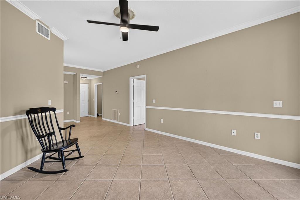 Neutral wall paint with chair rail molding, ceiling fan with integrated lighting, recessed entryway, and tile flooring