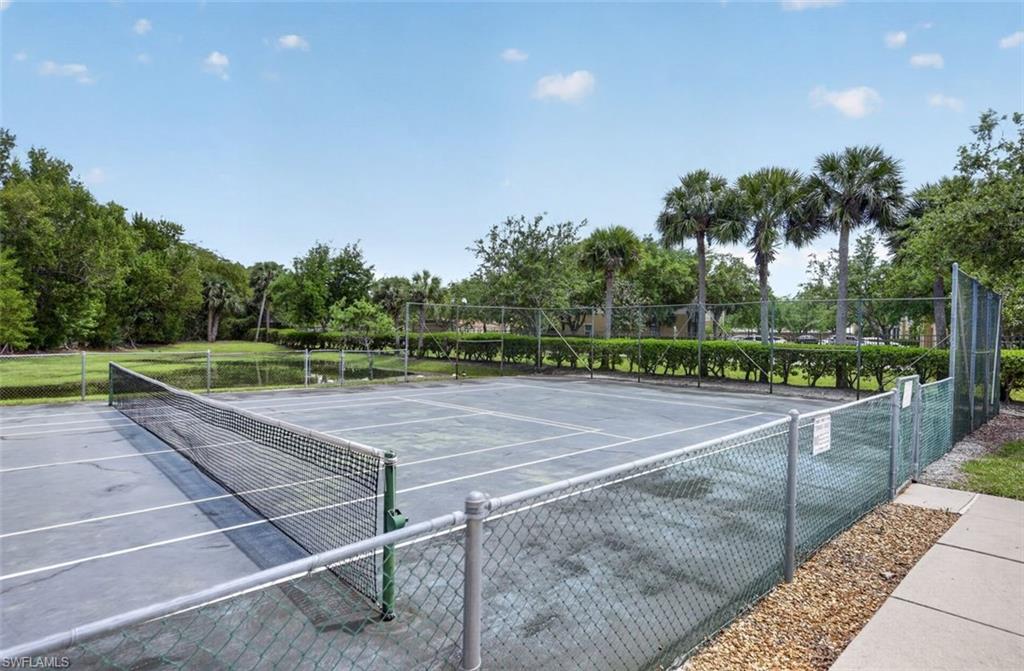 Tennis court with chain link fencing and mature landscaping