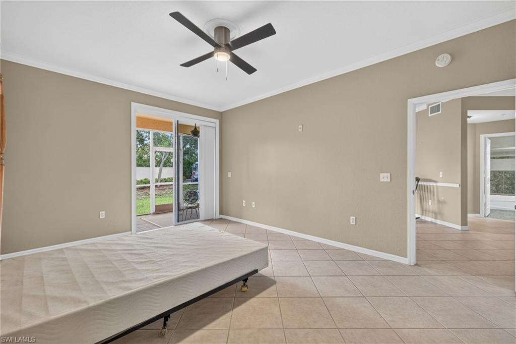 Tiled flooring extending throughout, ceiling fan with integrated lighting, sliding glass doors to a screened outdoor area, and neutral wall tones