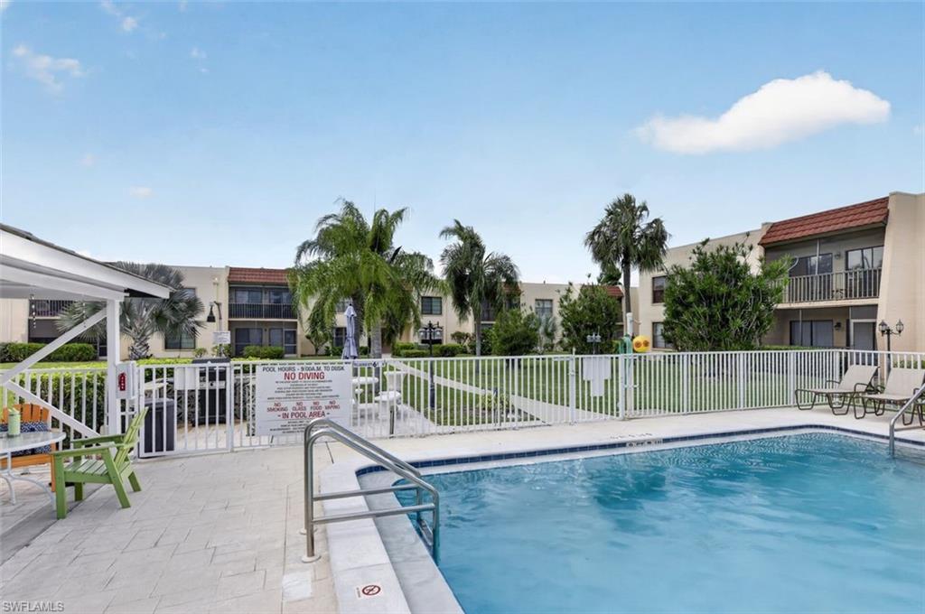 Swimming pool with integrated steps, surrounded by a white picket fence, and a paver patio