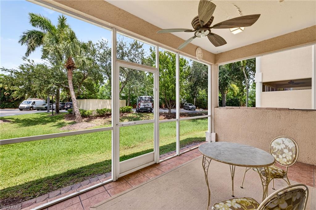 Screened patio featuring a ceiling fan, tiled flooring, and an exterior wall with a textured finish