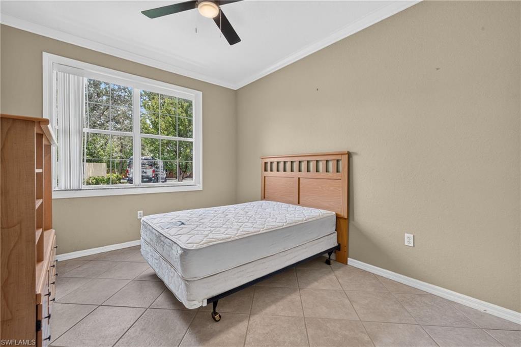 Window with exterior landscaping, tiled flooring, ceiling fan, and crown molding