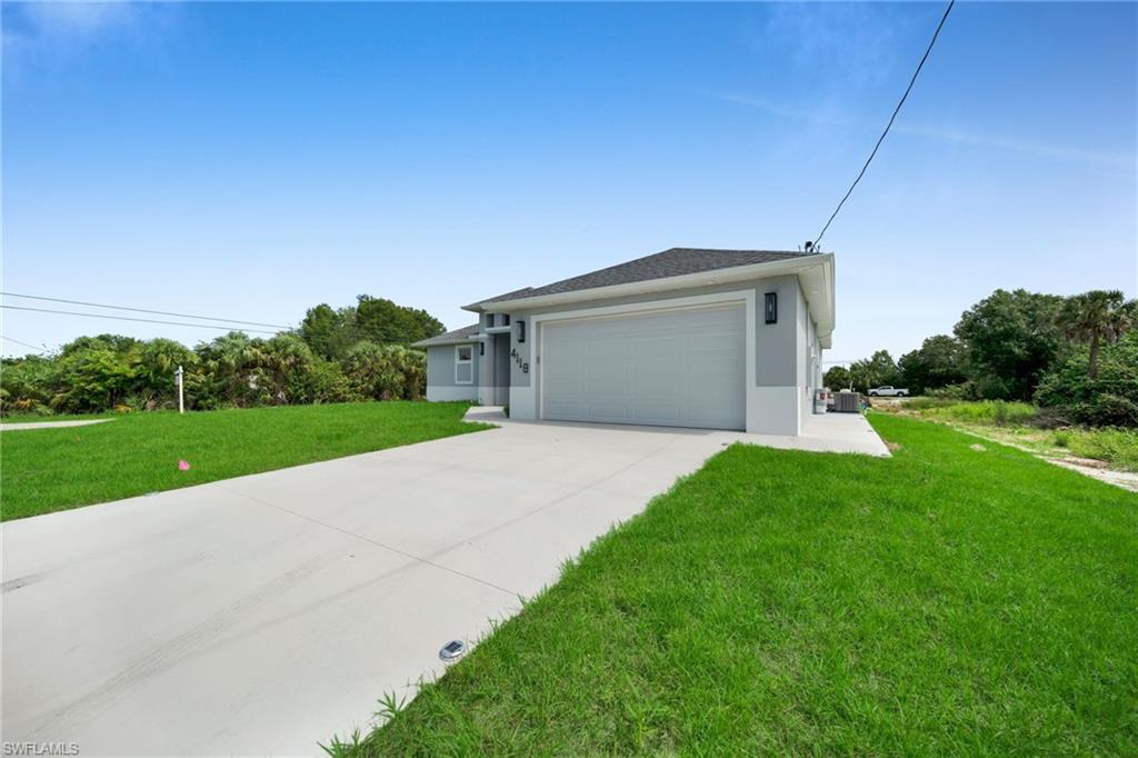 Contemporary exterior featuring a light gray facade, attached garage, concrete driveway, and manicured lawn