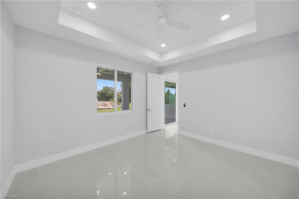 Recessed lighting and ceiling fan, tray ceiling, large window, interior door, and tile flooring
