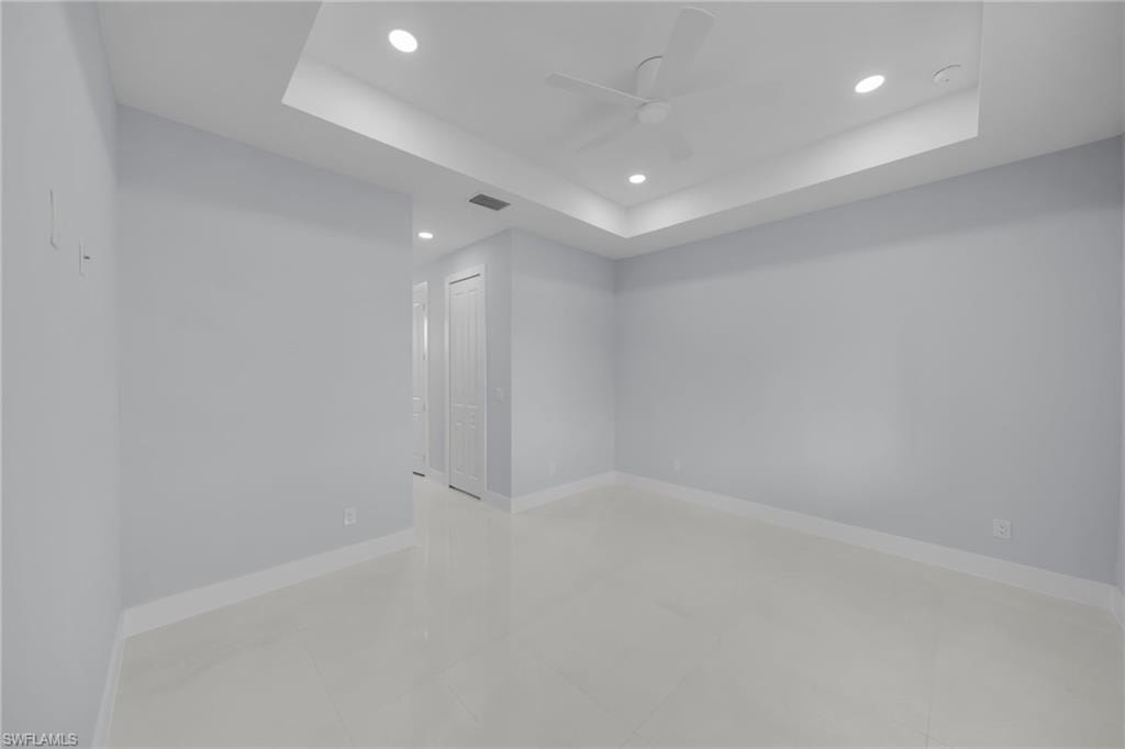 Tray ceiling with recessed lighting, ceiling fan, hard-surface flooring, and white paneled doors