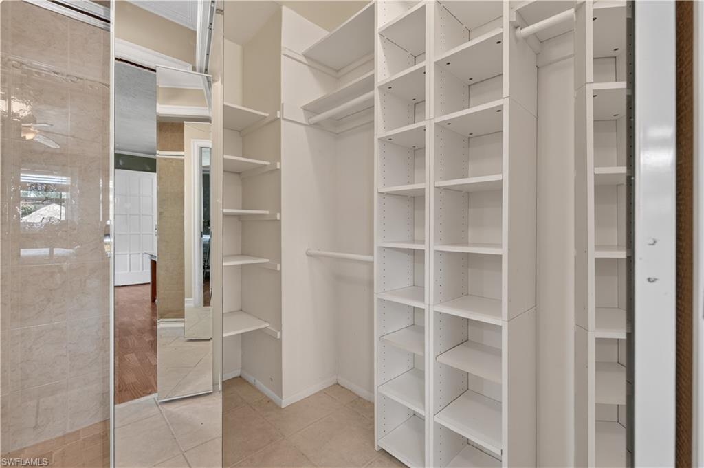 Built-in closet shelving and hanging rods with tile flooring