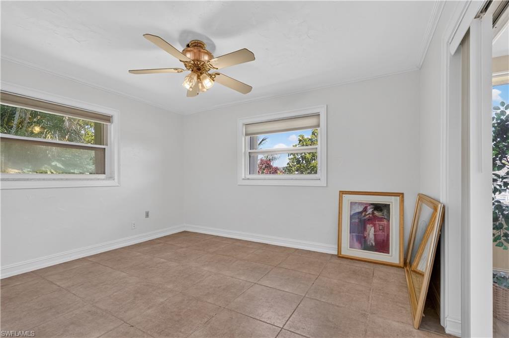 Neutral wall color, ceiling fan with integrated lighting, two windows with blinds, and tile flooring