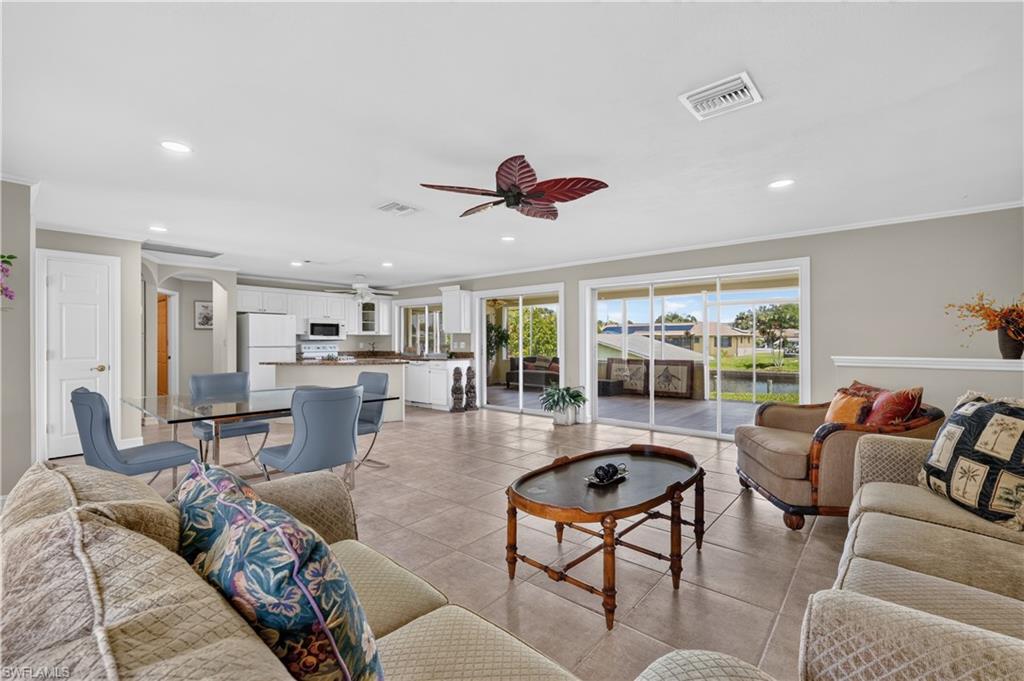 Open-concept living area featuring tile flooring, white kitchen cabinetry, a kitchen island, and sliding glass doors leading to the exterior