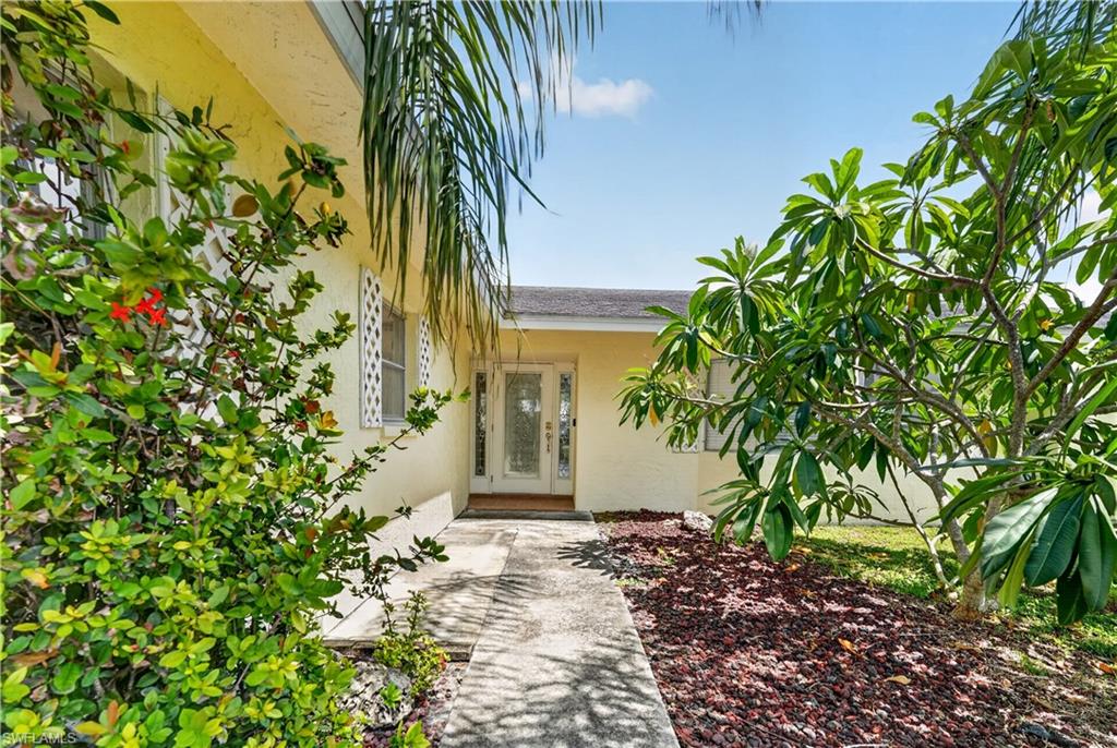 Exterior with light-colored stucco finish, white decorative window screens, and a covered entry