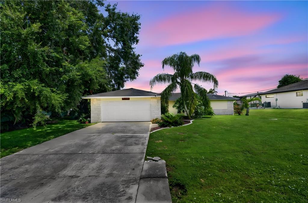 Concrete driveway, attached garage, well-maintained lawn, mature landscaping, and single-story exterior