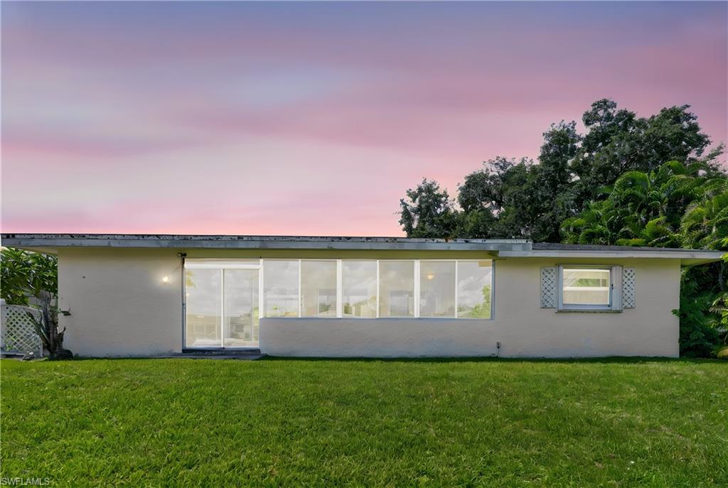 Expansive rear lawn with a light-toned stucco exterior