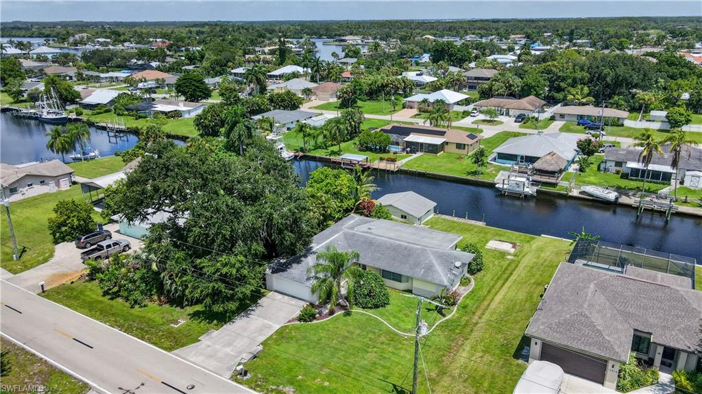 Waterfront home featuring a manicured lawn, mature landscaping, and direct canal access