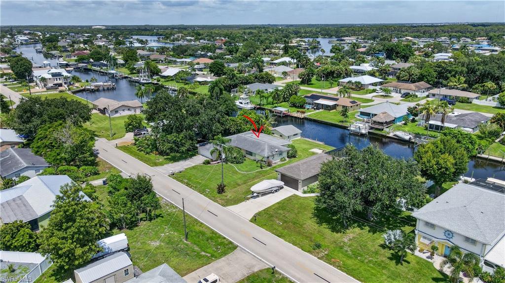 Waterfront property featuring direct canal access, mature trees, and a concrete driveway