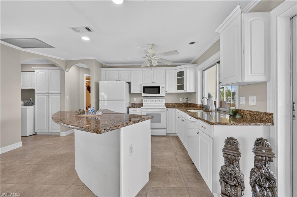 Kitchen featuring white cabinetry, granite countertops, tile flooring, a built-in microwave, and a ceiling fan
