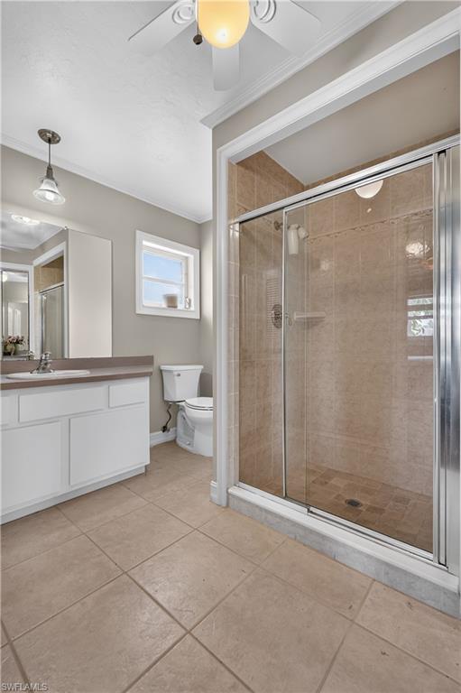 Tile flooring with a glass-enclosed shower, white vanity, and a window for natural light