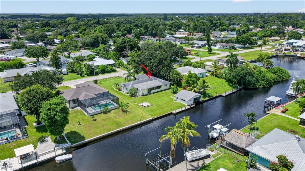 Waterfront property featuring a private boat dock, lush green landscaping, and mature trees