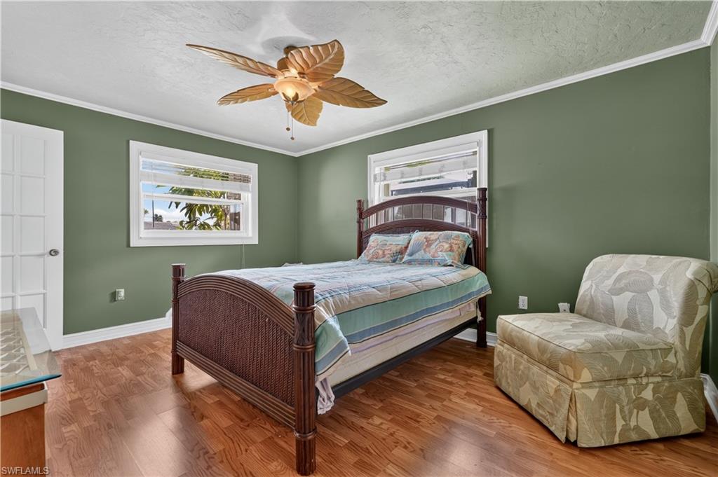 Wood-finish flooring, white trim, and a ceiling fan with palm-leaf-inspired blades