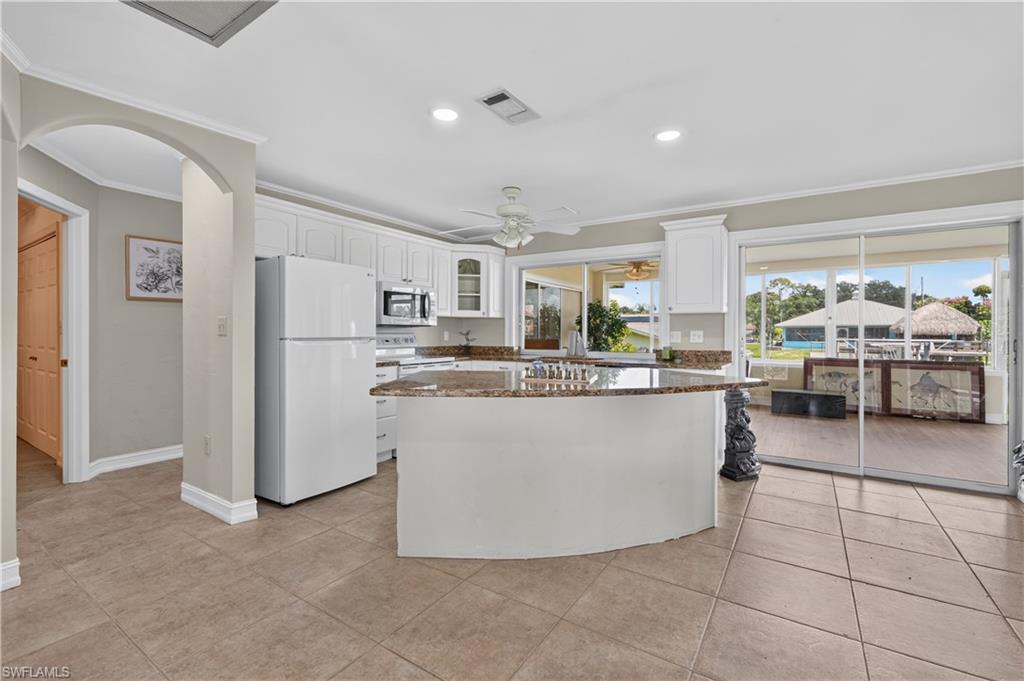 Kitchen with white cabinetry, granite countertops, tile flooring, and sliding glass doors