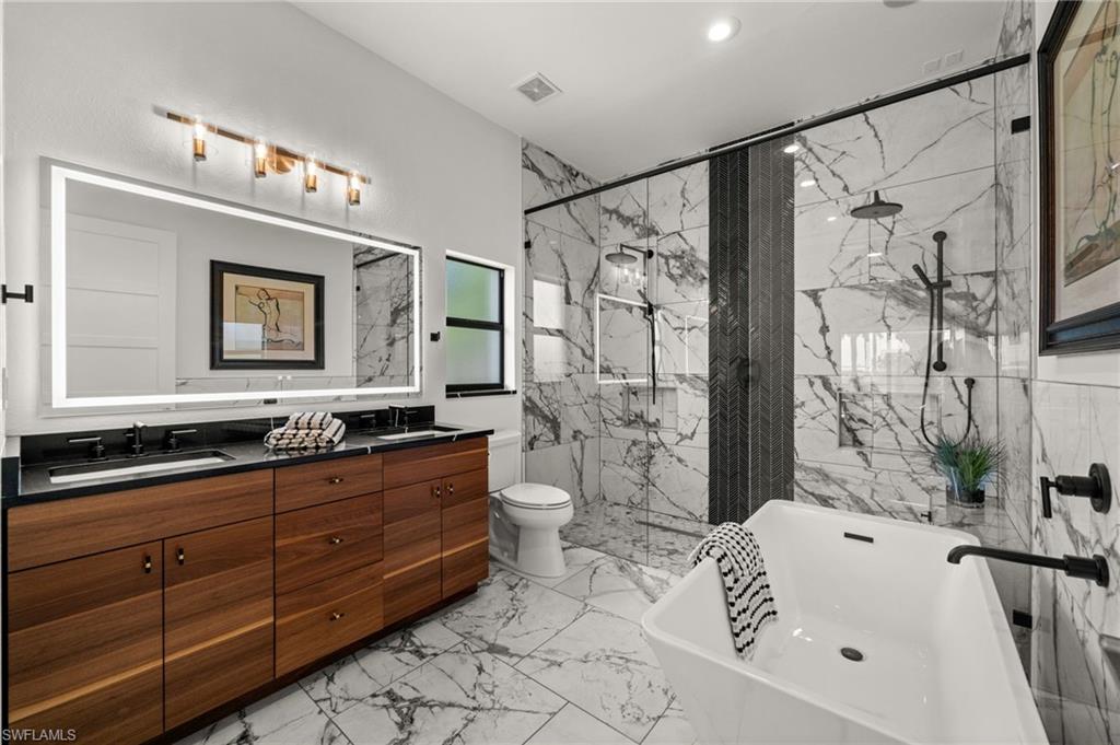 Primary bath with huge glass and tile double shower, separate tub and dual sinks