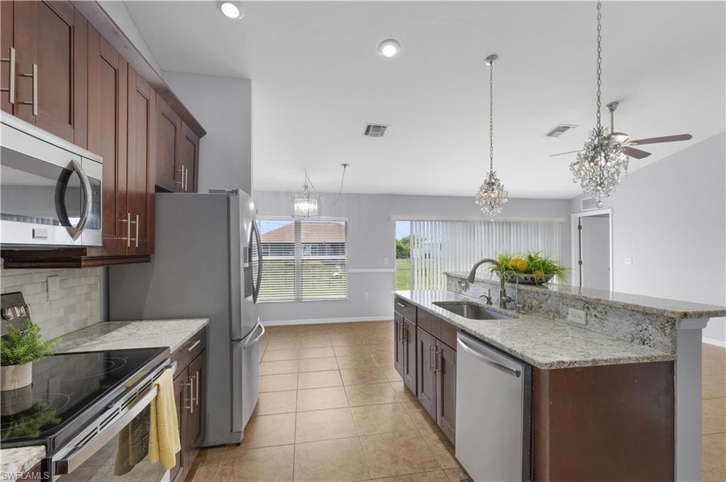 Kitchen featuring a large central island with granite countertops, stainless steel appliances, wood-finish cabinetry, and recessed lighting