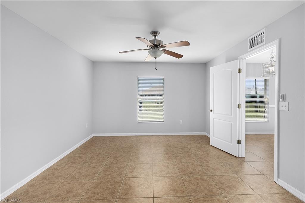 Neutral wall paint, tile flooring, window with blinds, ceiling fan with integrated lighting, and a paneled door