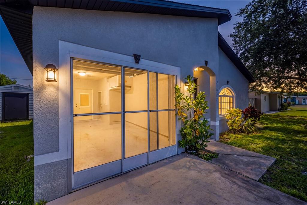 View of home in evening with lights on including in garage. An extension of living space with the screen door.