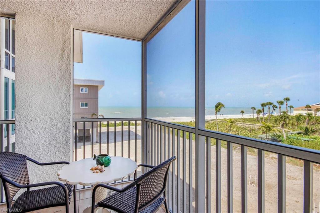 Elevated screened porch with expansive vistas across manicured grounds and coastal landscape, featuring floor-to-ceiling glass enclosure, aluminum railing, and mesh screening