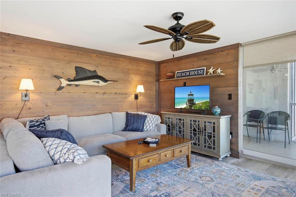 Warm wood-paneled walls create an inviting atmosphere in this recreational space, anchored by a light-gray upholstered sectional sofa and wooden coffee table with drawer storage