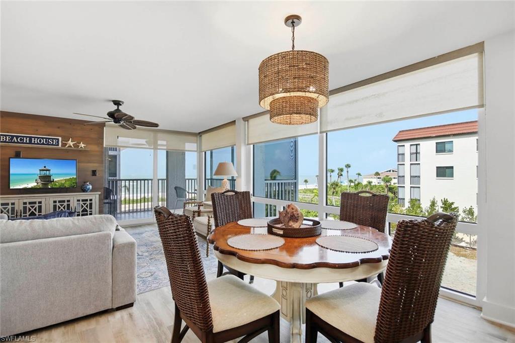 Open-concept living space with expansive windows, wood-finish flooring, and a ceiling fan
