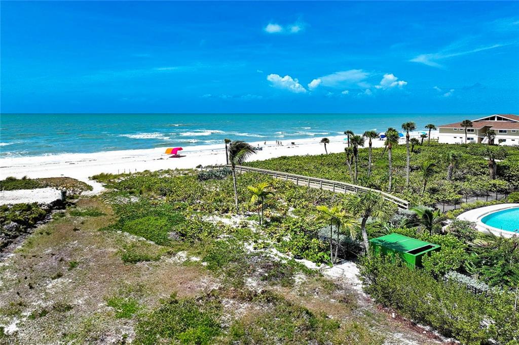Oceanfront property featuring expansive grounds with mature palm trees, manicured landscaping, and a wooden boardwalk leading to the sandy beach