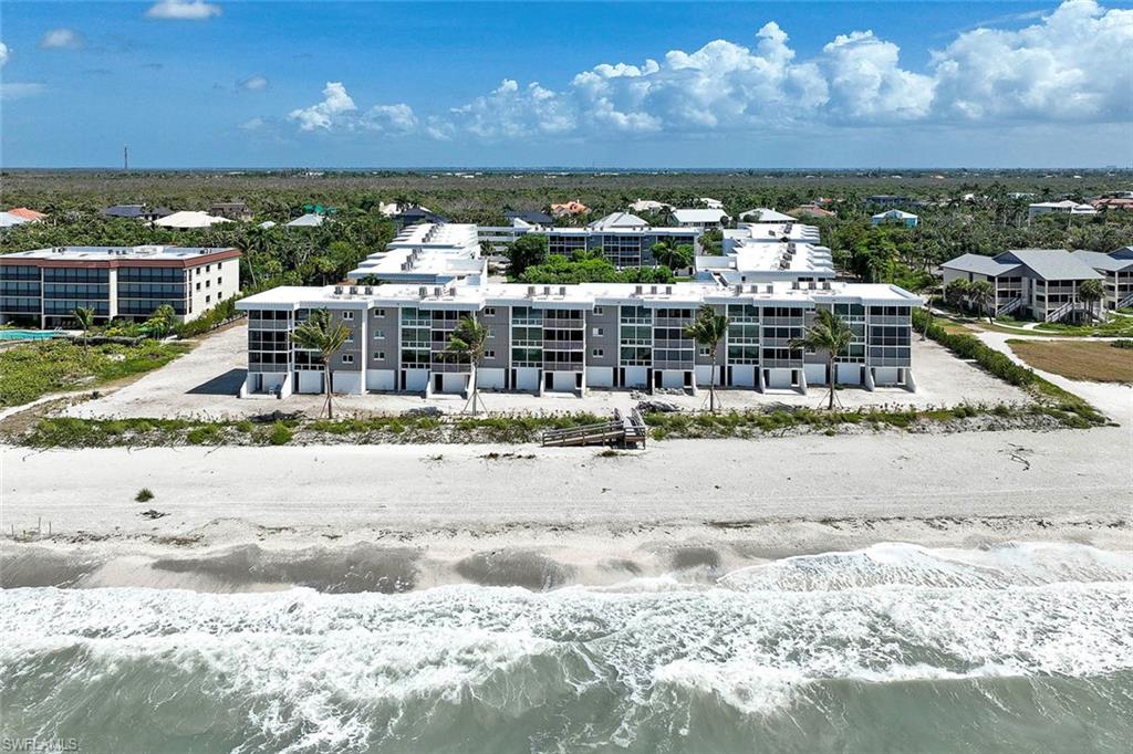 Oceanfront residential complex featuring contemporary architecture with multi-unit townhome design, expansive windows maximizing natural light, and direct beach access